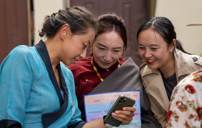 才永吉（左）向当地妇女展示如何使用智能手机在线学习健康知识。©联合国人口基金驻华代表处/王梓琪